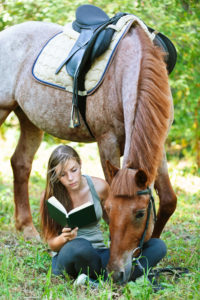 Rider with her horse reading a book